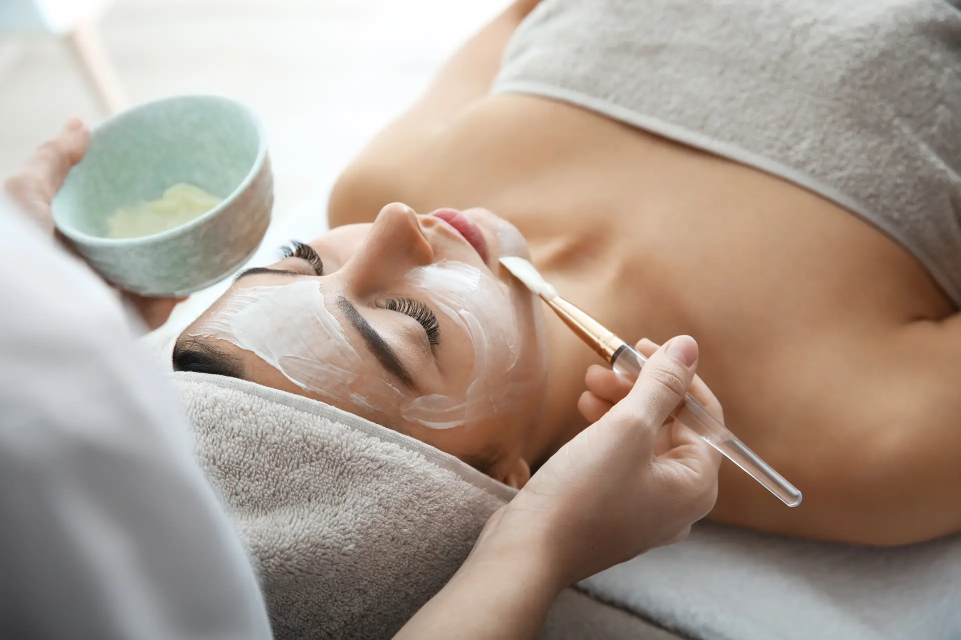 a woman lying down with a brush and a mask on her face