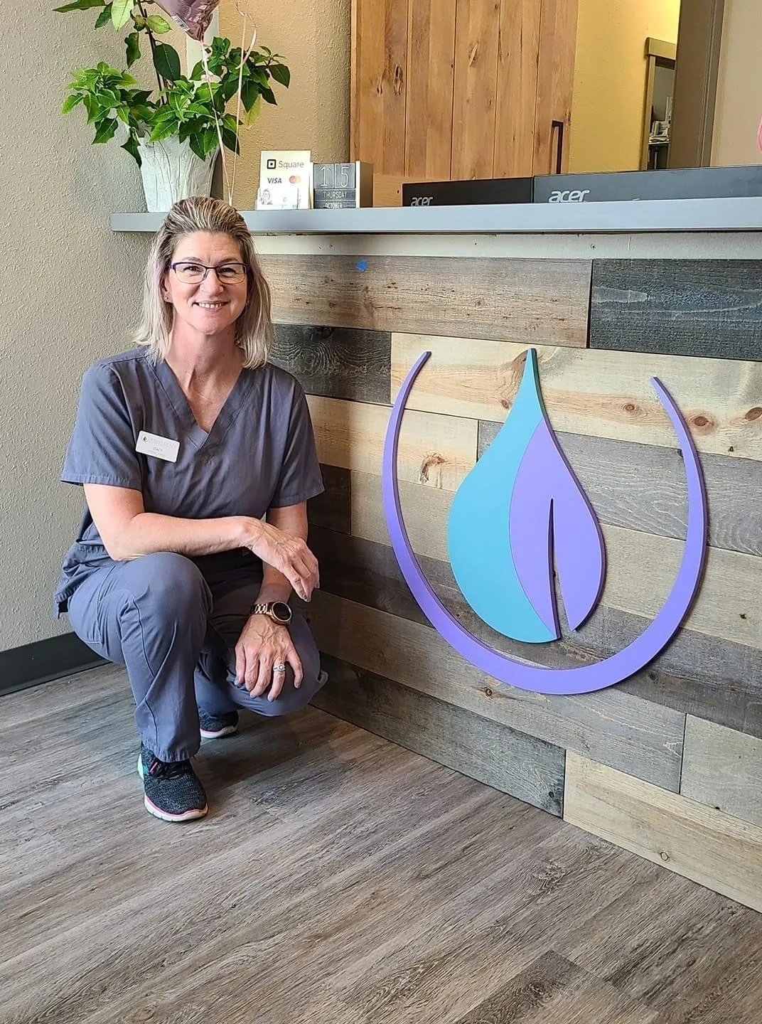 a woman in a scrubs squatting in front of a wall