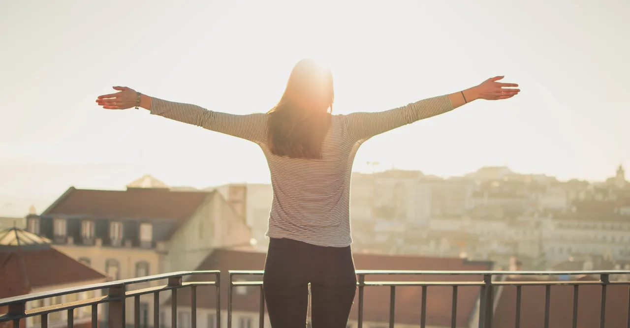 a woman standing on a balcony with her arms outstretched