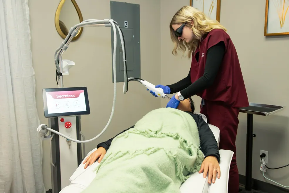 a woman using a device to remove a face - rs=w_984,h_656
