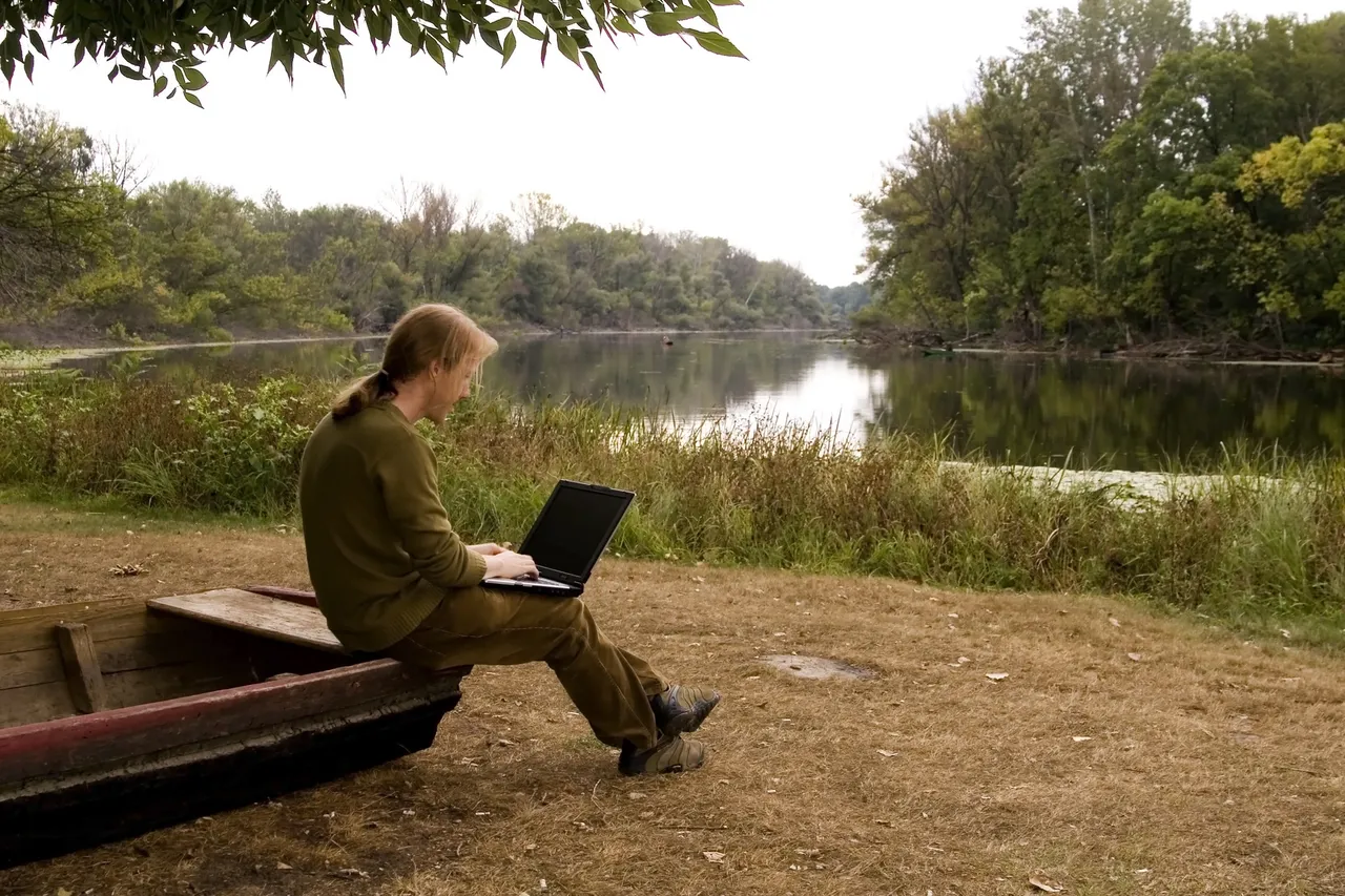A man sitting on a boat with a laptop, three ways to re establish a new normal after covid 19 1