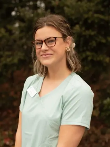 a woman wearing glasses and a green shirt - Maddie-About.webp