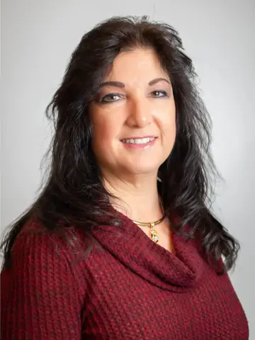 a woman with long dark hair wearing a red sweater - Melinda-About.webp